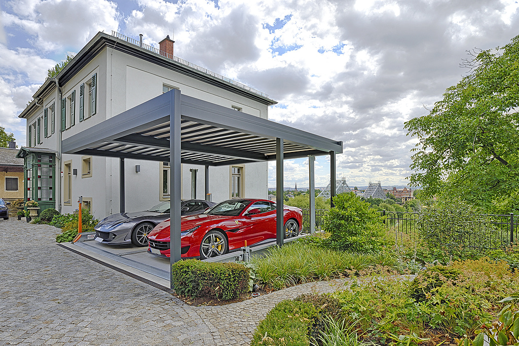 Side view of the carport and parking system, with 2 cars. In the background the property