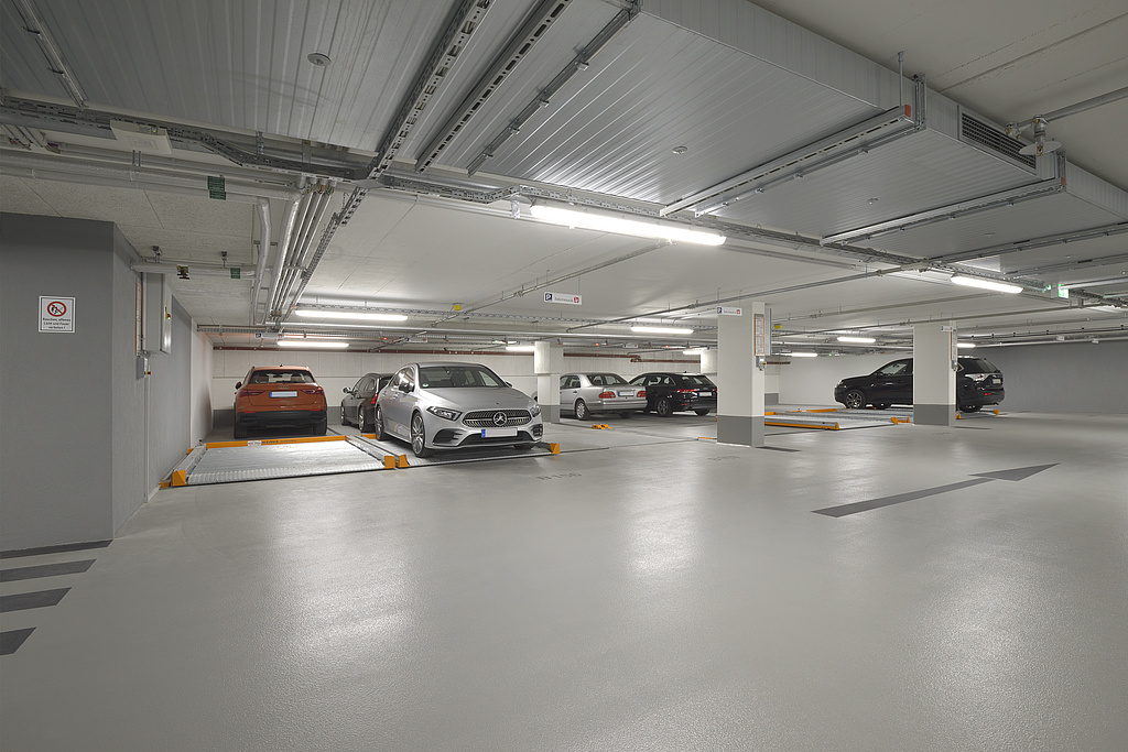 Cars are parked in an underground car park, parking pallets are installed in front of it