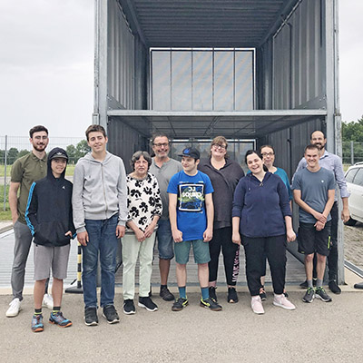 Outside, a group of happy people are standing in front of a parking system