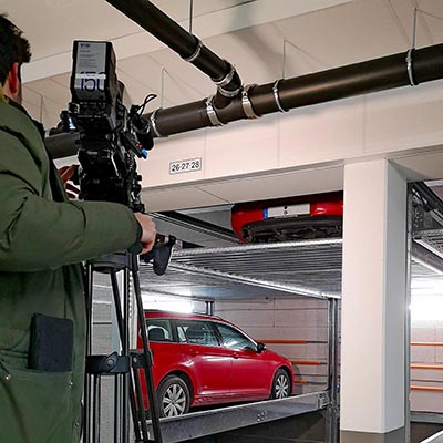 A cameraman in the foreground films a parking system