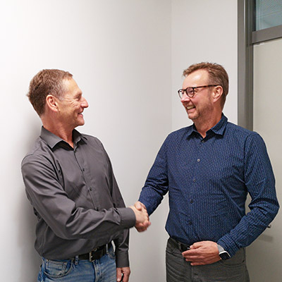 Two male persons look at each other and shake hands