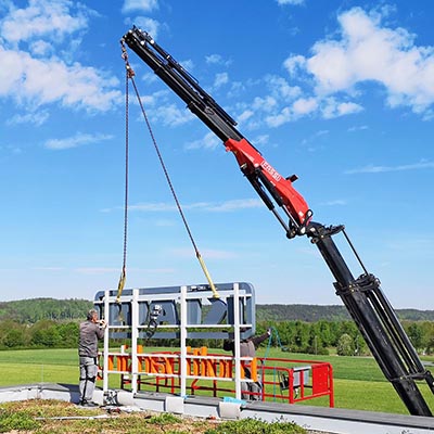 Auf dem Firmendach montiert ein Arbeiter die Leuchtreklame