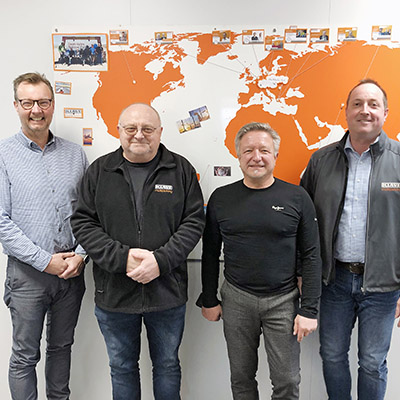 4 males in front of a wall with a world map