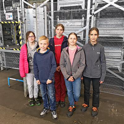 5 people in front of automatic shelving system